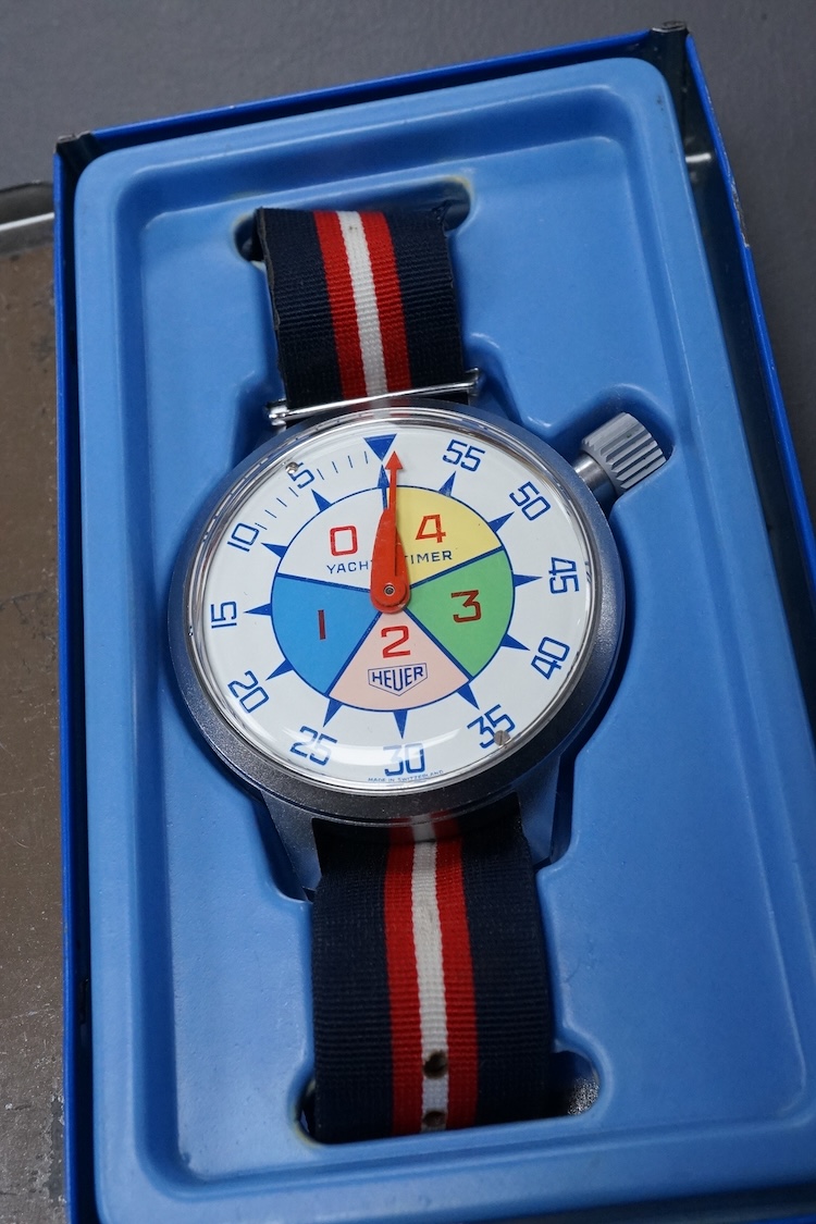 A 1970's steel cased Heuer Yacht Timer wrist stop watch, with polychrome dial, on a fabric strap, case diameter 52mm, with original Heuer tin box.